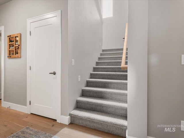 stairs with wood finished floors and baseboards
