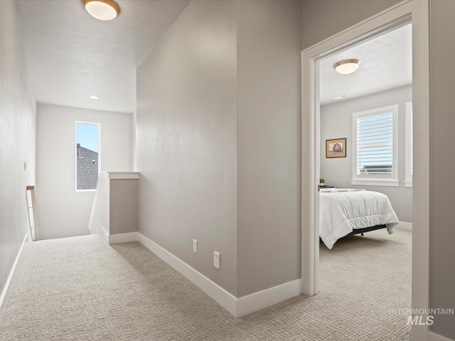 corridor with carpet, an upstairs landing, and baseboards