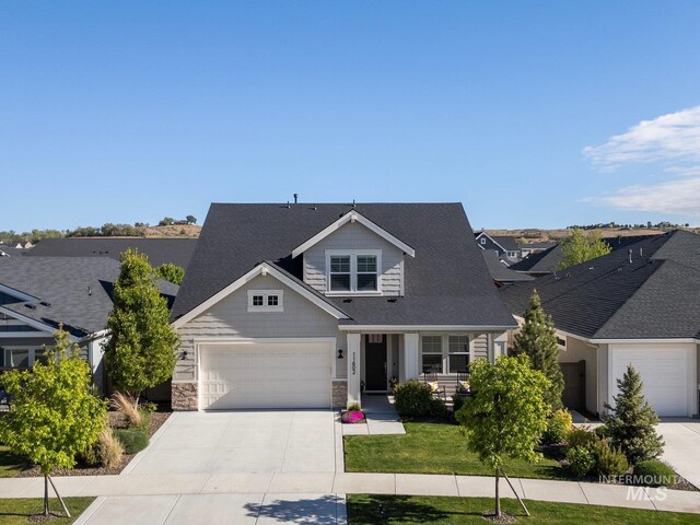 craftsman inspired home featuring driveway, a garage, stone siding, roof with shingles, and a front yard
