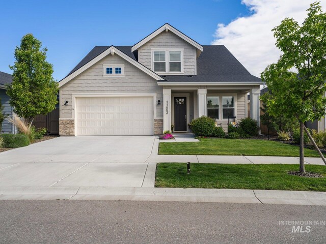 craftsman-style house with driveway, a front yard, and stone siding