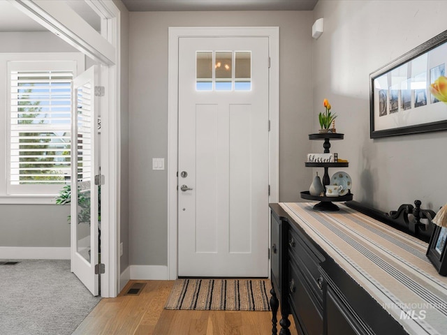 foyer entrance with light wood-style floors and baseboards