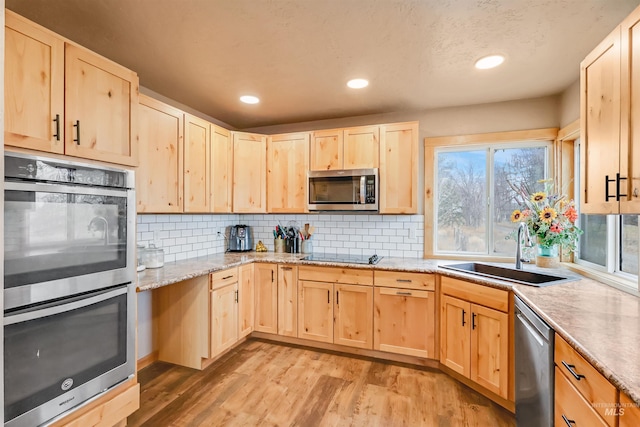 kitchen with sink, light brown cabinets, stainless steel appliances, light hardwood / wood-style flooring, and backsplash