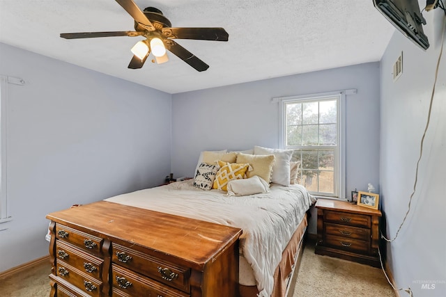 carpeted bedroom featuring a textured ceiling and ceiling fan