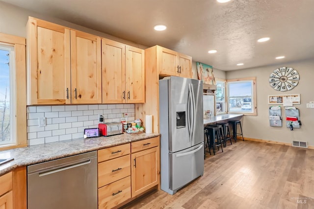 kitchen featuring light brown cabinets, light wood-type flooring, and stainless steel appliances