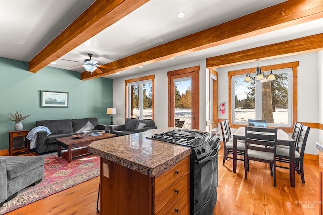 kitchen with tile counters, light wood-type flooring, open floor plan, and black range with gas cooktop