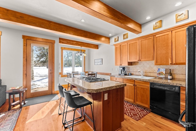 kitchen featuring tile countertops, a center island, a sink, black appliances, and backsplash