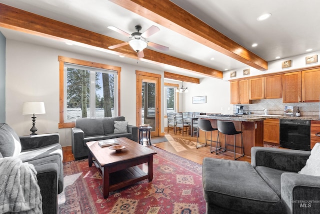 living area featuring ceiling fan with notable chandelier, wood finished floors, beam ceiling, and recessed lighting