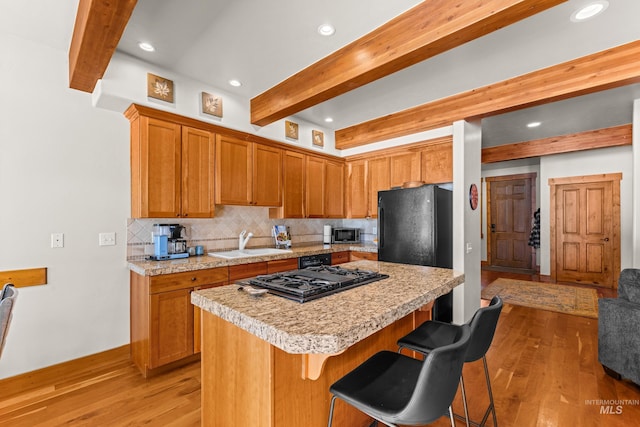 kitchen with light wood-type flooring, light countertops, a sink, and backsplash