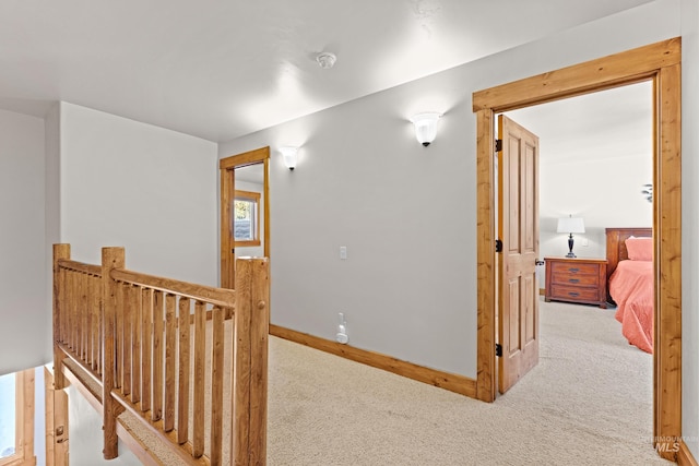 hallway featuring baseboards, carpet flooring, and an upstairs landing