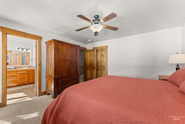 bedroom with ensuite bathroom, a ceiling fan, and light colored carpet