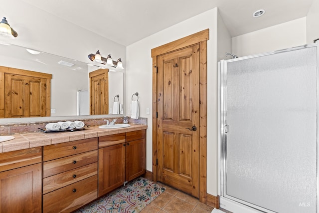 bathroom featuring double vanity, visible vents, a sink, a shower stall, and tile patterned floors