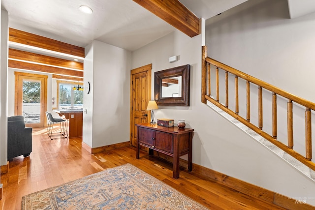 foyer entrance with wood-type flooring, stairs, baseboards, and beam ceiling