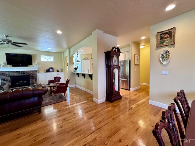 living room featuring a textured ceiling, ceiling fan, and light wood-style flooring