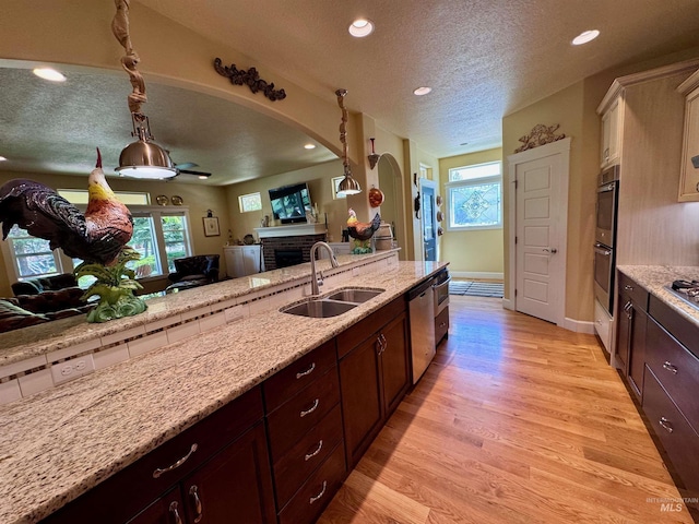 kitchen featuring a textured ceiling, arched walkways, a fireplace, a sink, and open floor plan