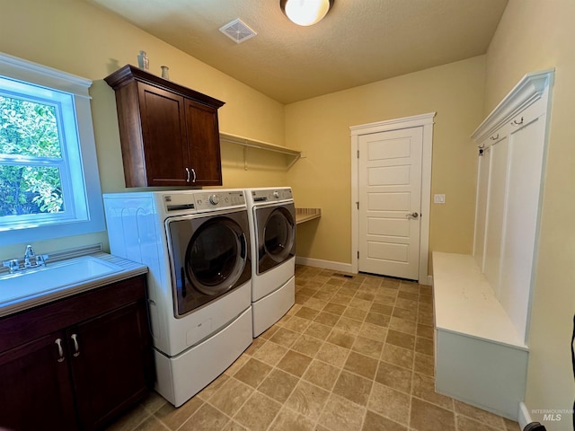 washroom featuring visible vents, a sink, cabinet space, and independent washer and dryer