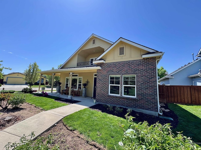 view of front facade with brick siding, board and batten siding, fence, and a front yard