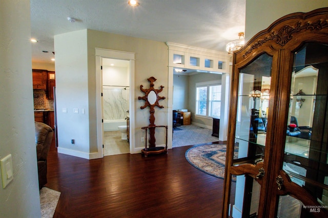 hall with baseboards, wood finished floors, and a notable chandelier