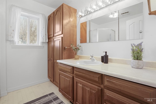 bathroom with vanity, visible vents, baseboards, and a stall shower