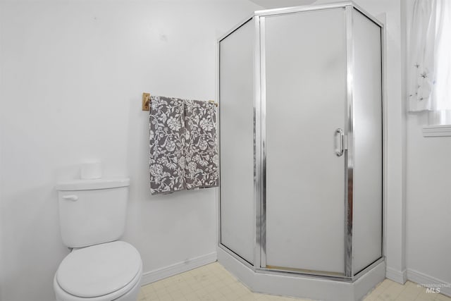 bathroom with tile patterned floors, baseboards, toilet, and a shower stall