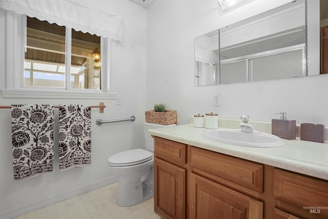 bathroom featuring vanity, toilet, and a shower with door