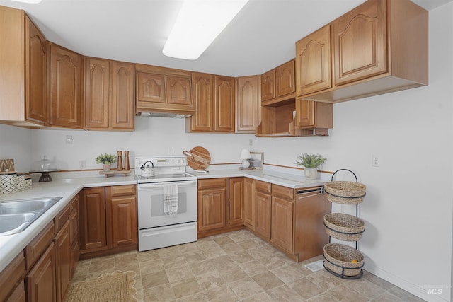 kitchen featuring brown cabinetry, light countertops, white electric range, and a sink