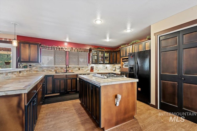 kitchen with light wood finished floors, stainless steel appliances, light countertops, and backsplash