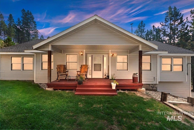 back of property at dusk featuring a lawn