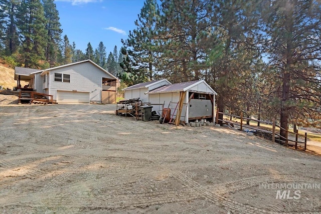 view of home's exterior with an attached garage, fence, an outbuilding, and driveway