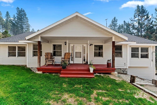 rear view of house featuring a lawn and a shingled roof