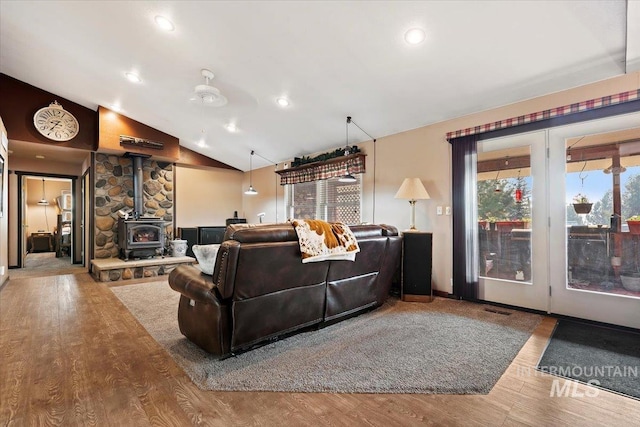 living room featuring recessed lighting, wood finished floors, a wood stove, and lofted ceiling