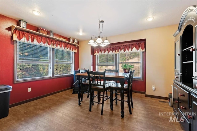 dining space featuring baseboards, a notable chandelier, and wood finished floors