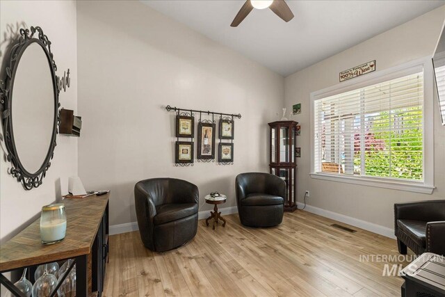 sitting room featuring a ceiling fan, vaulted ceiling, light wood-style flooring, and baseboards