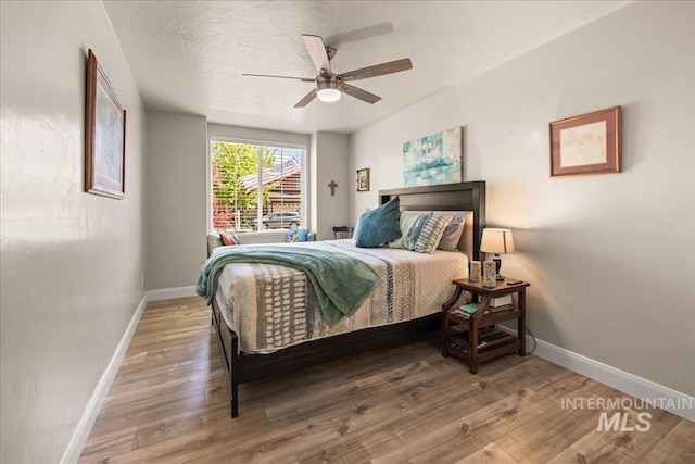 bedroom with baseboards, wood finished floors, and a ceiling fan
