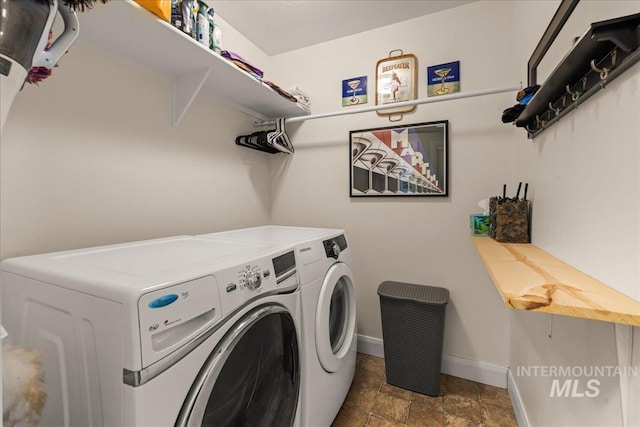 laundry room featuring washing machine and dryer, baseboards, and stone finish flooring