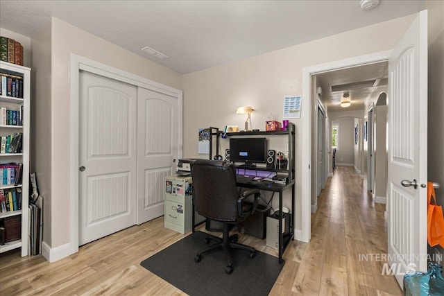 home office with light wood-style floors, baseboards, and arched walkways