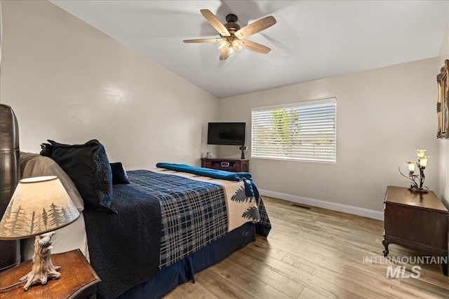 bedroom with lofted ceiling, baseboards, light wood-style flooring, and a ceiling fan