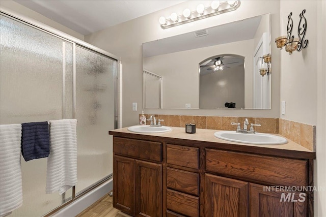 bathroom with ceiling fan, a stall shower, double vanity, and wood finished floors