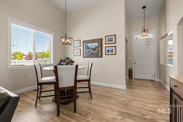 dining room featuring high vaulted ceiling, baseboards, a chandelier, and light wood finished floors