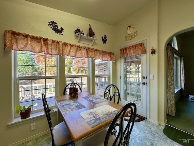 dining space featuring baseboards and arched walkways