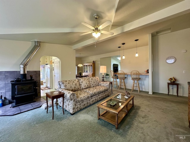 living area featuring a wood stove, arched walkways, ceiling fan, and carpet flooring