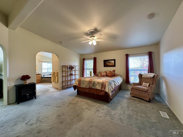 bedroom with a textured ceiling, visible vents, arched walkways, carpet, and a ceiling fan