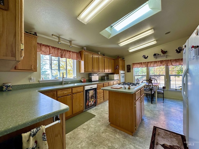 kitchen with a sink, a center island, light floors, a wealth of natural light, and white appliances