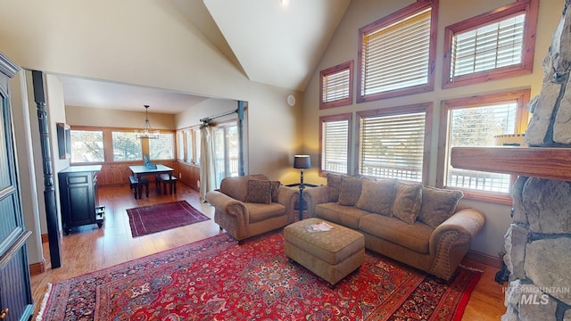 living room with a chandelier, high vaulted ceiling, and light hardwood / wood-style flooring