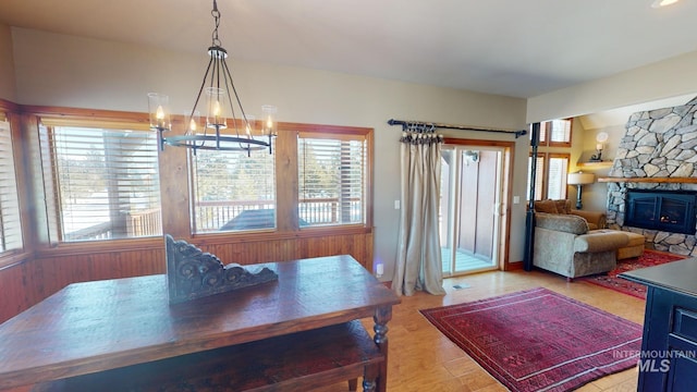 dining space featuring an inviting chandelier, a fireplace, and light hardwood / wood-style floors