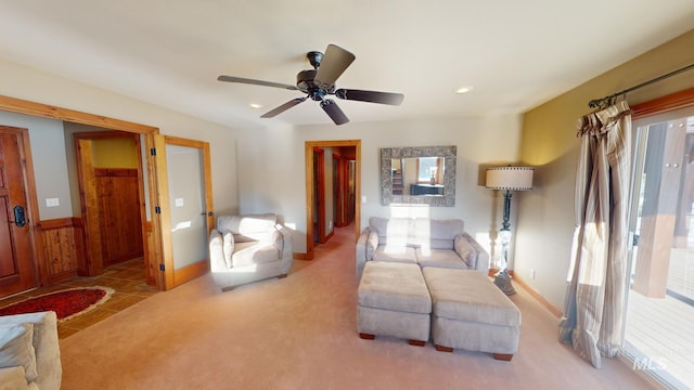 living room with ceiling fan, light carpet, and wooden walls