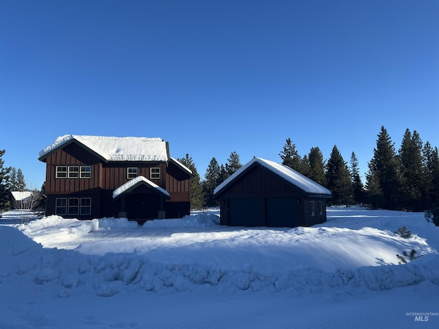 snow covered rear of property with a garage