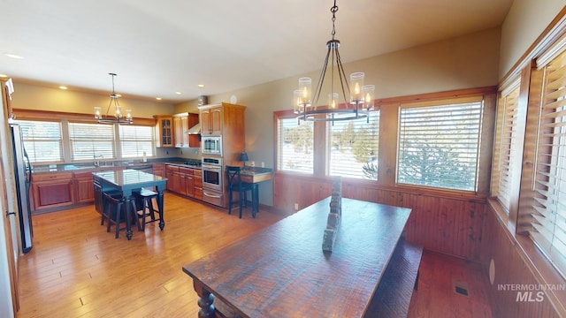 dining room featuring an inviting chandelier, wooden walls, and light wood-type flooring