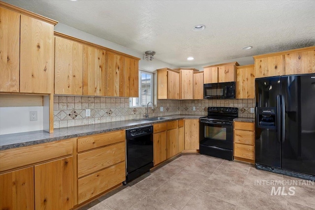 kitchen featuring black appliances, backsplash, dark countertops, and a sink