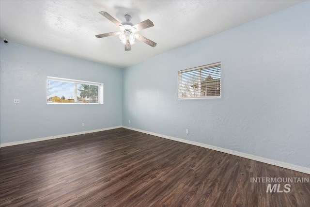 spare room featuring dark wood-style floors, baseboards, and a ceiling fan