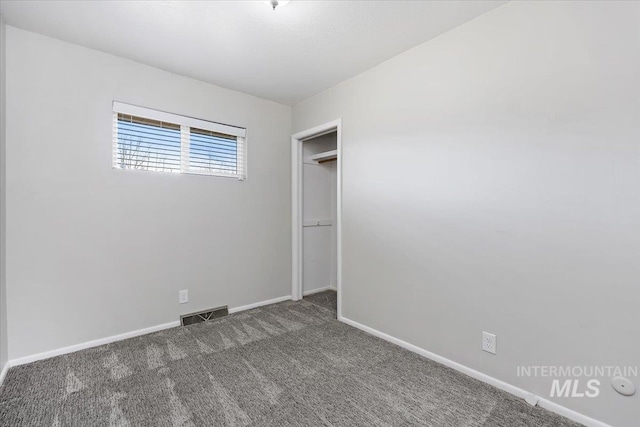 empty room with carpet, visible vents, and baseboards